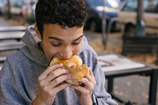 Young man enjoying a delicious burger outdoors
