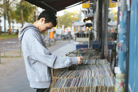 Young man browsing through vinyl records on a sidewalk