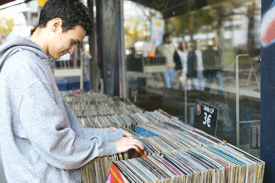 Young man shopping for vinyl records outdoors