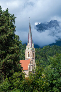 Campanile neogotico della Christuskirche a Innsbruck con picchi alpini tra le nuvole, Tirolo, Austria