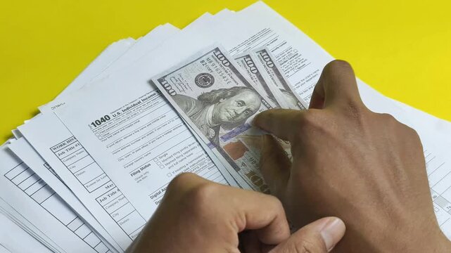 Cash placed on top of a Form 1040 tax document, representing income, taxation, financial planning, and tax payment.