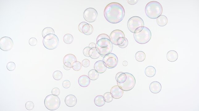 虹色に輝くシャボン玉が白い背景に舞い上がる幻想的な光景