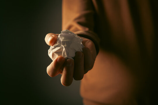 Man holding crumpled paper in his hand.