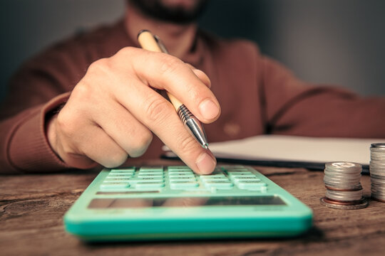 man hand with calculator and coins on table, business and finance concept