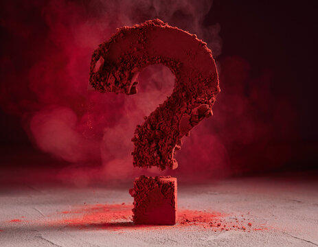 A close-up shot shows a large red question mark made of powder on a textured surface, with red smoke billowing in the background.