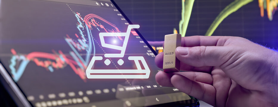 Online gold purchasing concept. Hand holding a gold bar with glowing shopping cart icon and financial trading charts