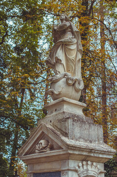 Ancient cemetery monuments featuring ornate gravestones, weathered stone sculptures and historic tombs surrounded by trees. Atmospheric old-world funerary architecture and timeless memorial details 