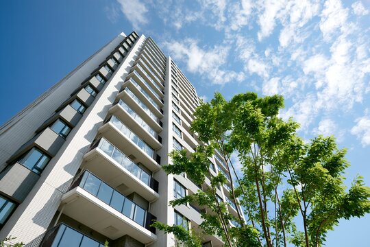 見上げる新築分譲マンションと青空都会に映える緑豊かな風景