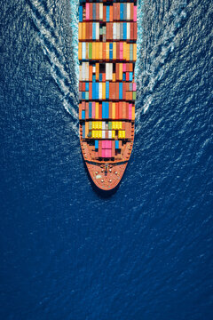 Aerial overhead view of a large container cargo ship sailing over the ocean with copy space as a banner for logistics and transport