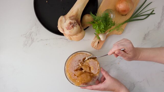 Dense, collagen-rich gelled bone broth texture tested with spoon in a premium kitchen