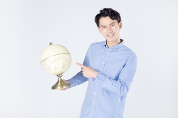 Smiling young man holding and pointing at globe in studio © CungHao