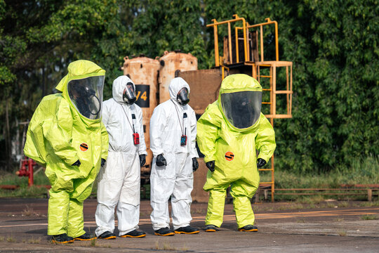Hazmat response team walking together through an industrial facility during hazardous materials emergency preparedness and workplace safety training in full protective suits