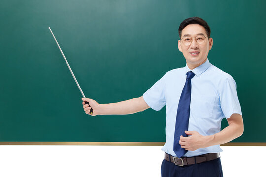 Smiling male teacher presenting with pointer in front of classroom chalkboard