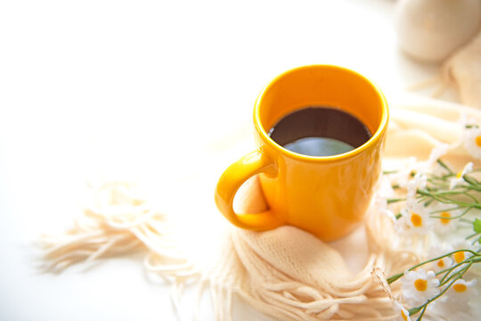 Coffee morning.  Yellow steaming cup of hot coffee for relax after working hobbies crochet on white wooden near window with flowers