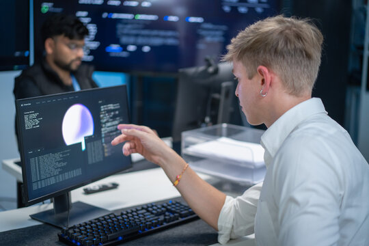 Programmers collaborating in modern office with high tech computers and software development interface