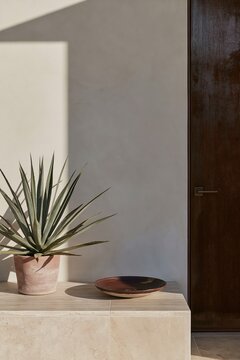 Cozy desert entry nook featuring low travertine bench, terracotta pot with agave, and corten steel door illuminated by warm afternoon light
