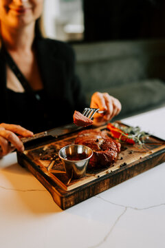 Woman eats a tender steak dinner with savory sauce at a restaurant during the evening hours