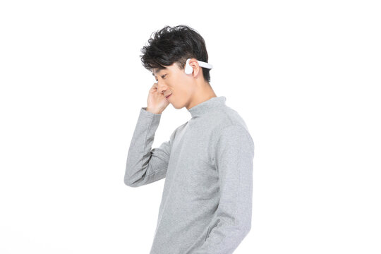 Young man listening with wireless headphones in side profile on white