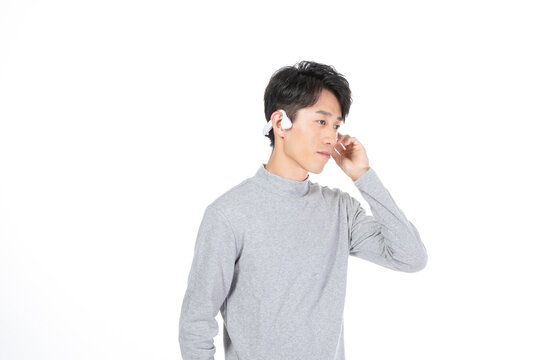 Young man wearing wireless earbuds on white background