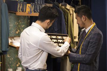 Fototapeta premium Customer Selecting Cufflinks with Menswear Consultant in Tailor Shop