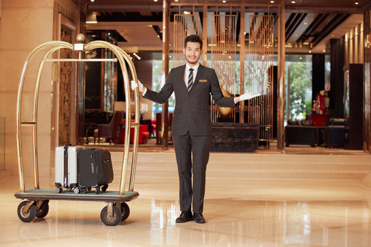 Hotel bellhop with luggage cart in luxury lobby