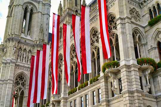 Close-up of the Gothic Revival facade of Vienna City Hall adorned with row of Austrian national flags, Vienna