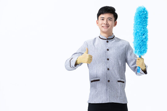 Smiling cleaner holding feather duster and giving thumbs up on white background