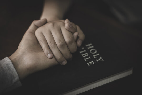 Two people holding hands in prayer, sharing faith, hope, and support through Christian worship and devotion to God.
