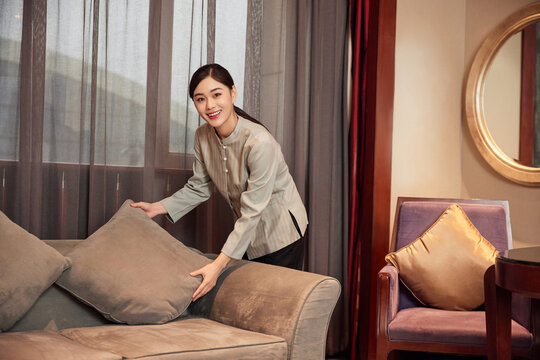 Housekeeper arranging sofa cushion in hotel suite living room