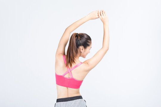 Back view of athletic woman stretching in pink sportswear