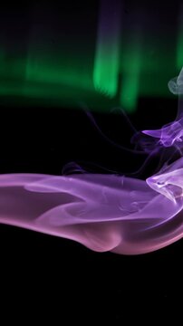 Abstract Purple and Green Smoke Swirling Against a Black Background