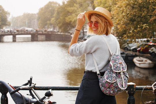 Happy traveler girl enjoying Amsterdam city. Smiling woman on Amsterdam canal, Netherlands, Europe