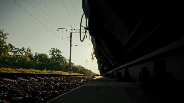 A concept for rail freight transportation and modern transport logistics. A close-up of a freight train traveling along rails and sleepers on a bright day in the countryside