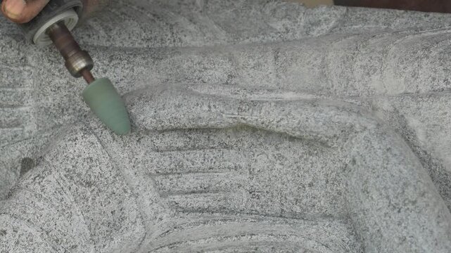 Sculptor carving detailed granite relief with rotary grinder in India 