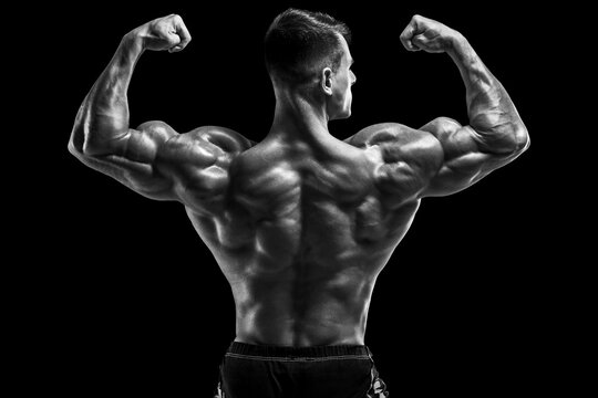 Muscular man showing back muscles on black background. Strong male rear view