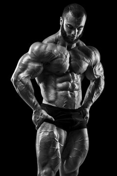Bodybuilder man on the black background. Strong male naked torso abs