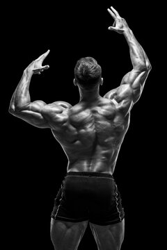 Muscular man showing back muscles on black background. Strong male naked torso