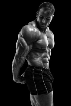 Muscular man on the black background. Strong male naked torso abs