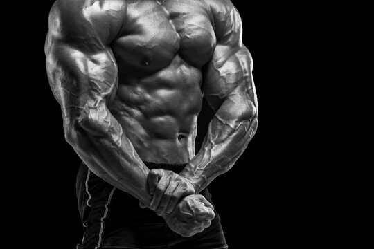 Muscular man showing muscles on black background. Strong male naked torso abs