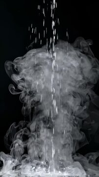 Water Droplets Falling Through Swirling White Smoke Against Black Background