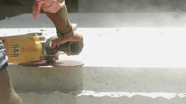 Sculptor grinding stone pedestal with power tool dust flying