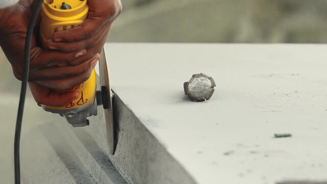 Worker polishing stone block with angle grinder in artisan sculpture workshop India