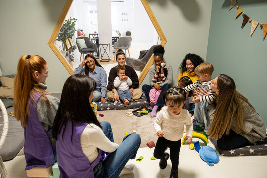 Teachers and children interacting, playing and learning together in a bright kindergarten room