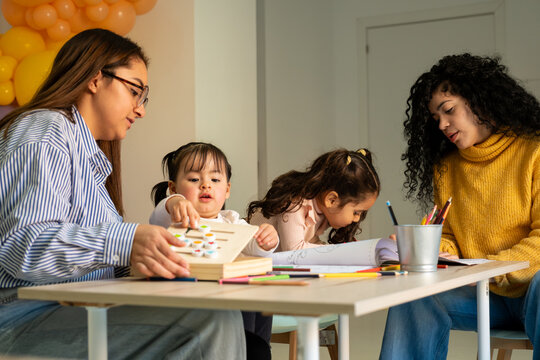 Teachers and young children enjoying interactive learning activities around a table