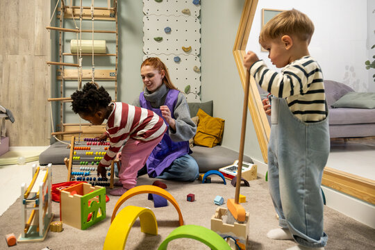 Teacher and multi ethnic children playing with Montessori toys in a classroom