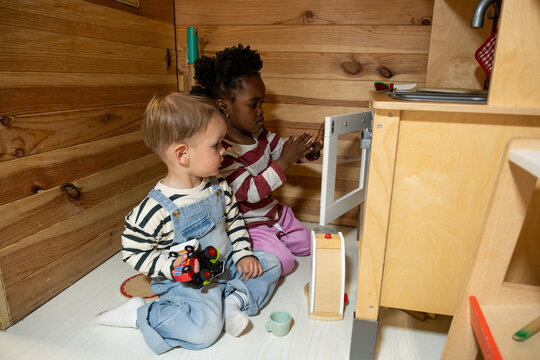Diverse children enjoying creative play with a toy kitchen in a cozy kindergarten classroom