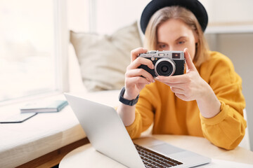 Naklejka premium Female photographer taking a photo with camera while working on laptop