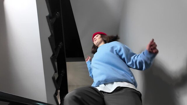 Young Woman in Red Beanie Freestyle Dancing Hip Hop on a Staircase in a Modern Building Lobby