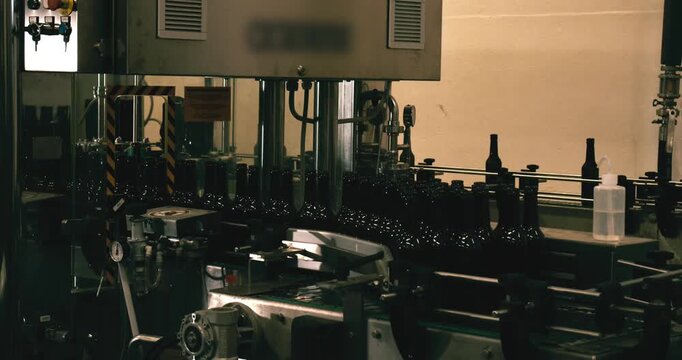 Unfinished beer bottles entering bottling machine in brewery Berlin