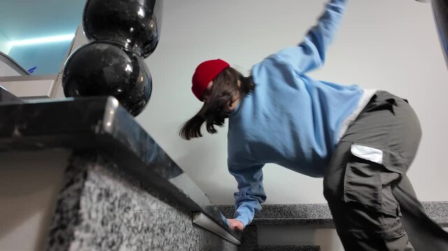 Young Woman in Red Beanie Freestyle Dancing Hip Hop on a Staircase in a Modern Building Lobby